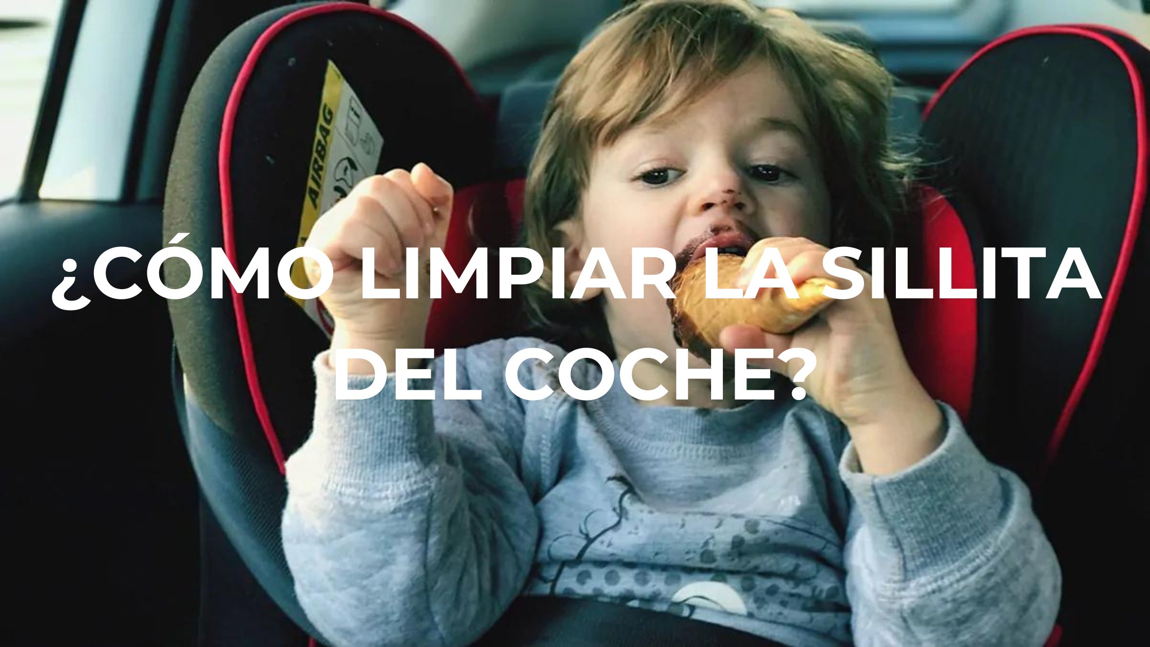 Bebé con la boca manchada de chocolate en la sillita del coche comiendo un dulce