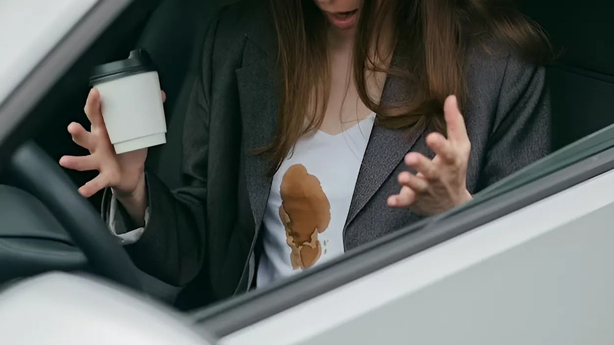Mujer con una mancha de café en la camiseta en el interior del coche