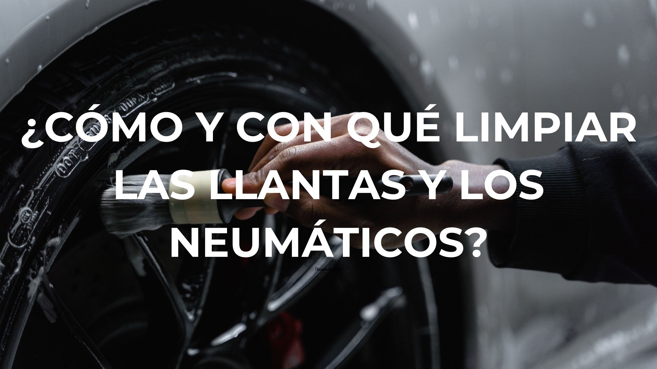 Hombre limpiando la llanta negra y el neumático de un coche blanco con un pincel