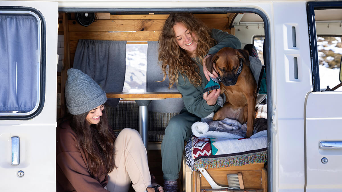 Dos mujeres y un perro en el interior de una caravana