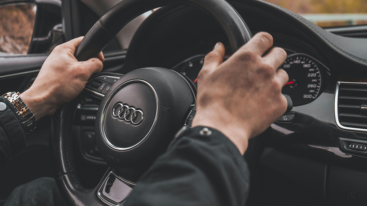 Manos de un hombre sujetando un volante de un coche Audi