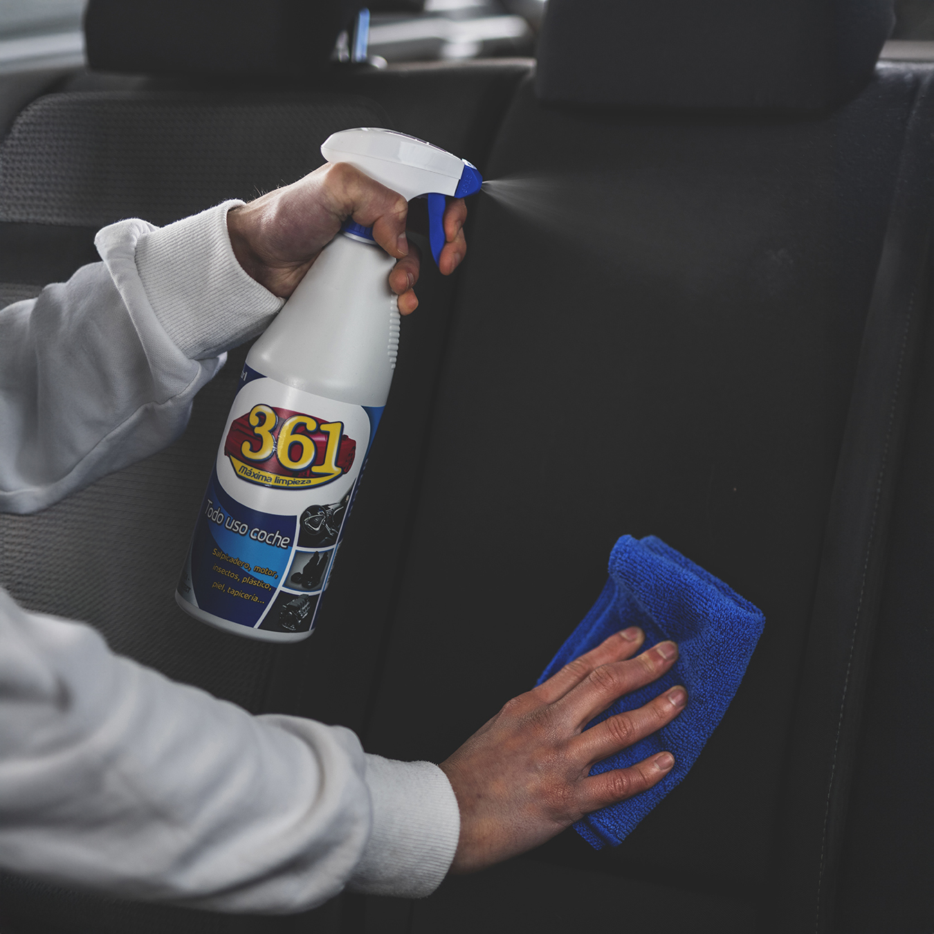 Persona pulverizando 361 Todo Uso en el asiento de un coche mientras limpia con una microfibra azul