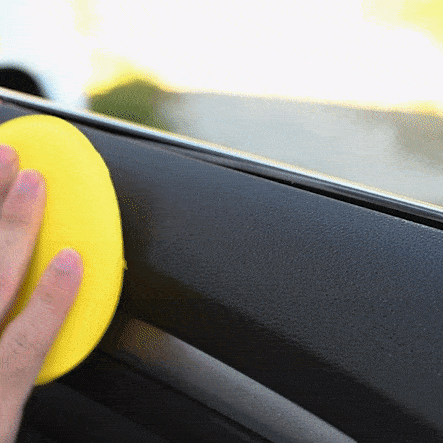 Hombre aplicando sobre los plásticos interiores de un coche con un aplicador amarillo