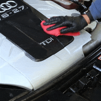 Hombre con guantes negros retira restos del producto con una microfibra roja quedando el motor limpio