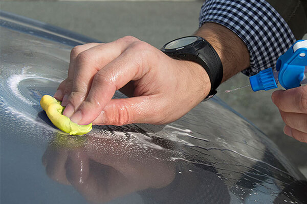 Sisbrill Claybar Amarilla Fina de 200 gramos siendo utilizada sobre el capó de un coche negro para descontaminar la pintura