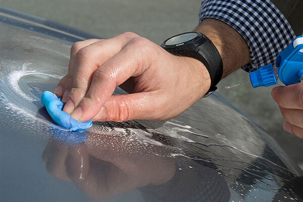 Sisbrill Claybar Azul Media de 200 gramos siendo utilizada para descontaminar la pintura de un coche negro