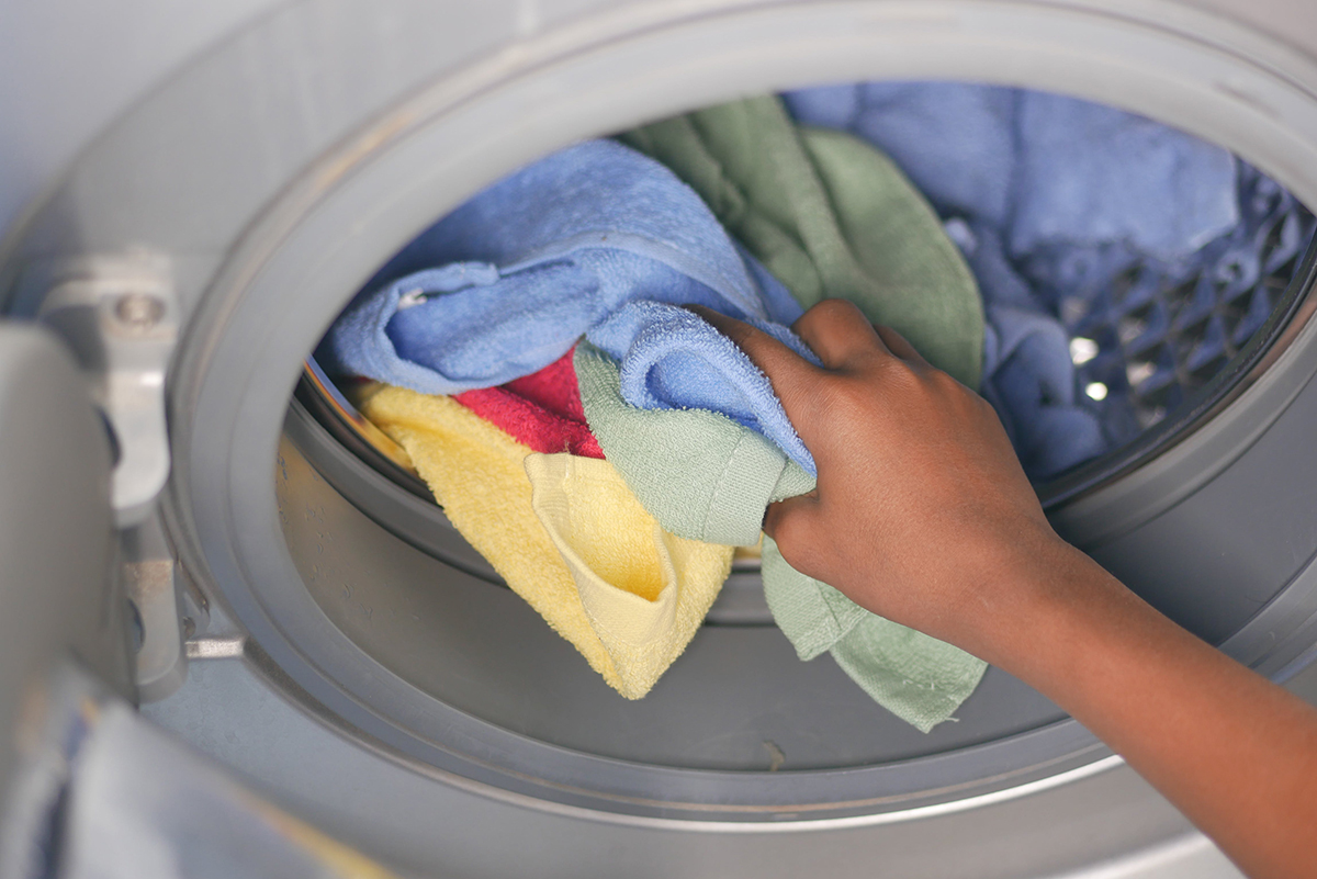 Mano de una persona introduciendo microfibras en una lavadora