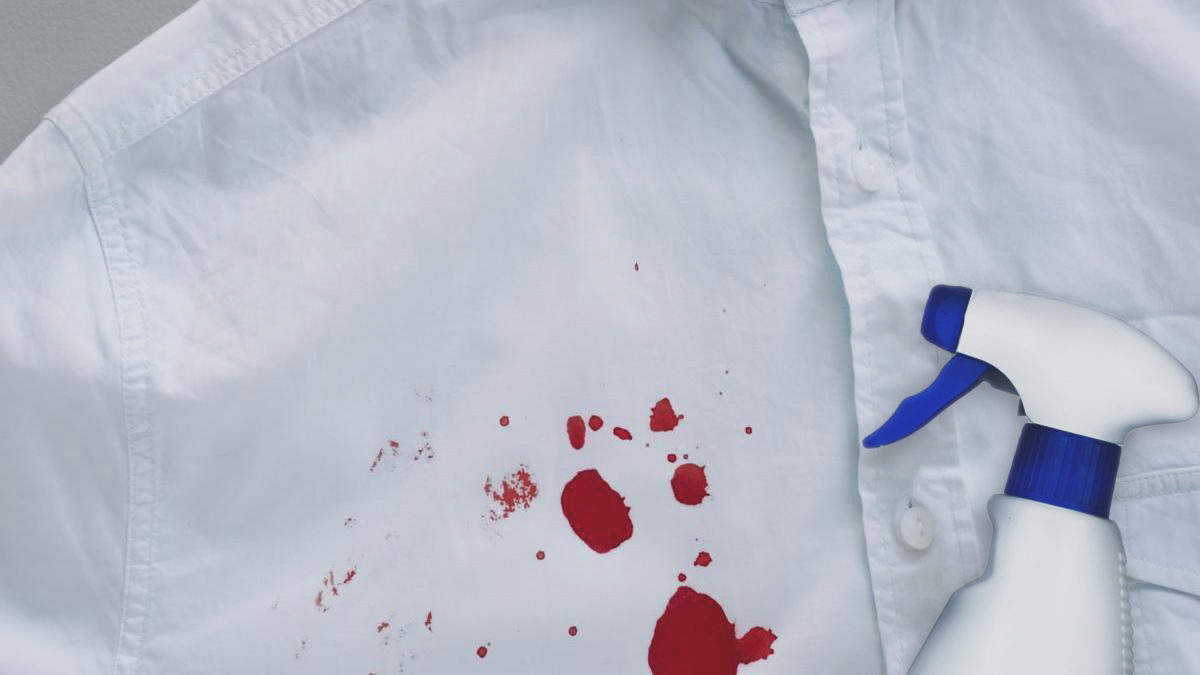 Camisa blanca con manchas de sangre al lado de una botella de spray