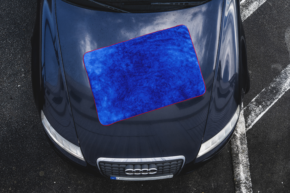 Toalla de secado azul sobre el capó de un coche de color oscuro
