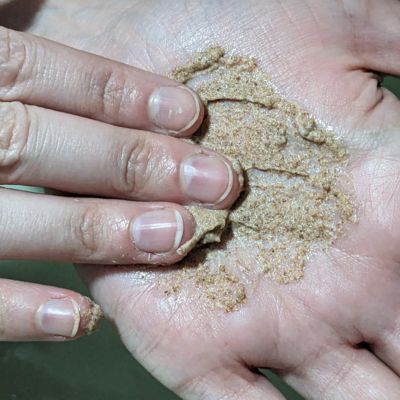 Manos de una persona frotándose con una pasta exfoliante de limpieza, posiblemente para eliminar suciedad o residuos.